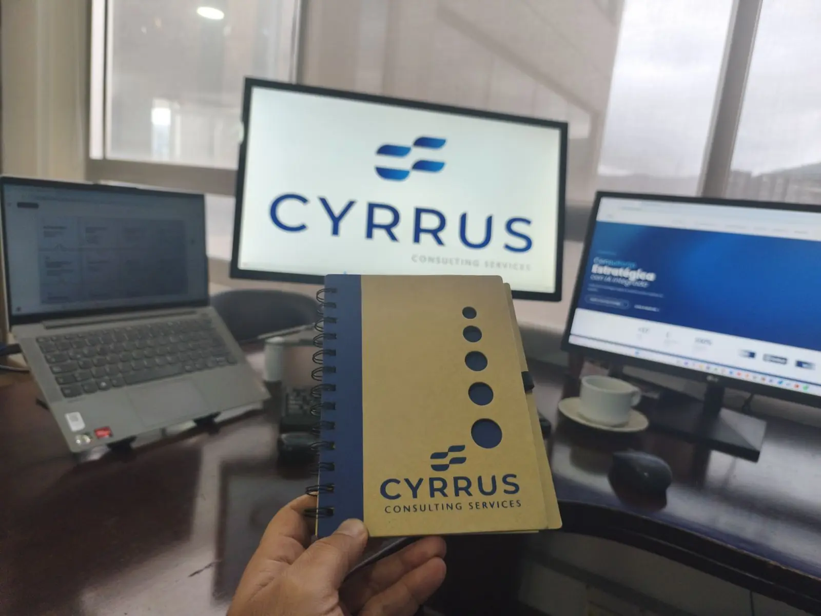 Consultor de Cyrrus con notebook frente a pantallas de trabajo
