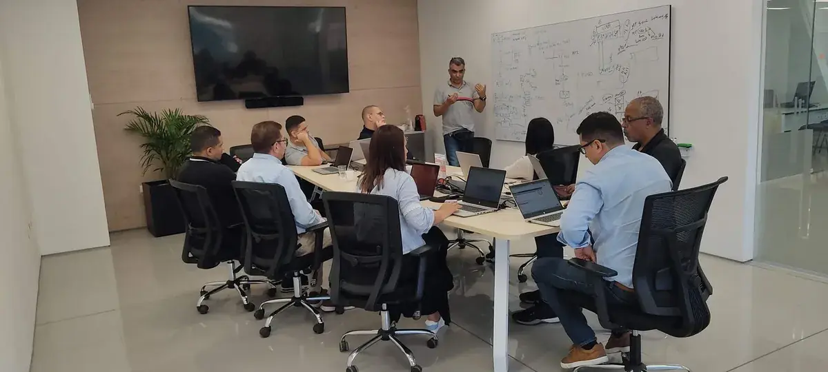 Working session in a meeting room, with a facilitator in front of a whiteboard of diagrams